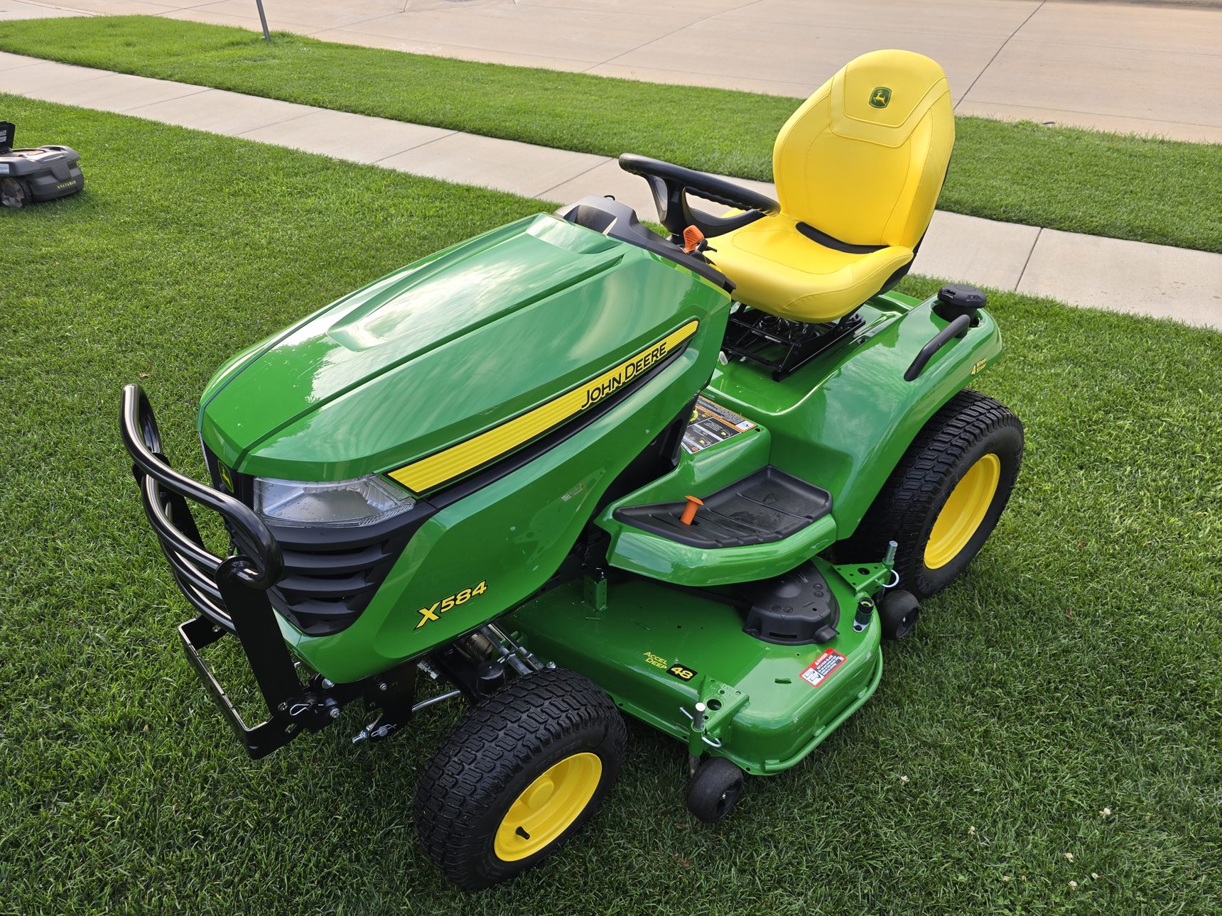 Darin's actual green John Deere X584 in his front yard, with a robotic mower in the background